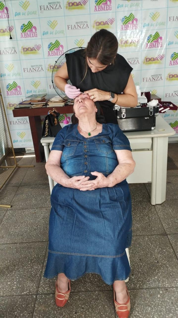 Voluntária cuidando de uma idosa durante ação de beleza e bem-estar